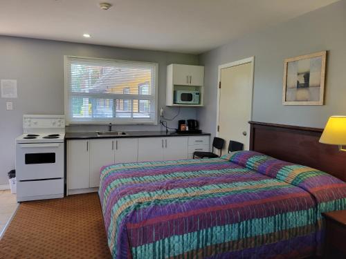 a hotel room with a bed and a kitchen at Knights Inn Cobourg in Cobourg