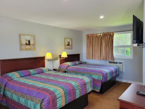 a hotel room with two beds and a tv at Knights Inn Cobourg in Cobourg