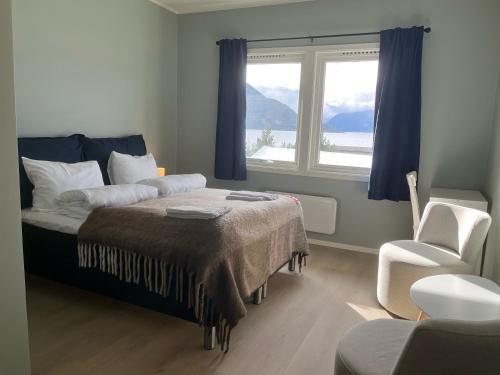 a bedroom with a bed and a chair and a window at Skibotn Hotel in Skibotn