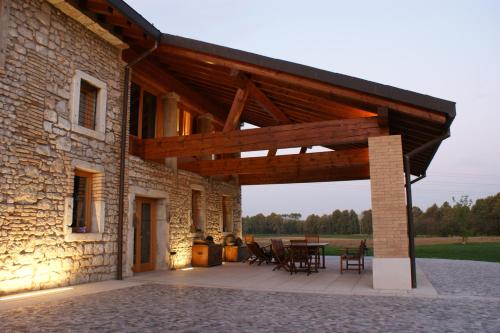 a stone house with a wooden roof and a table at Country House Due Fiumi in Sacile