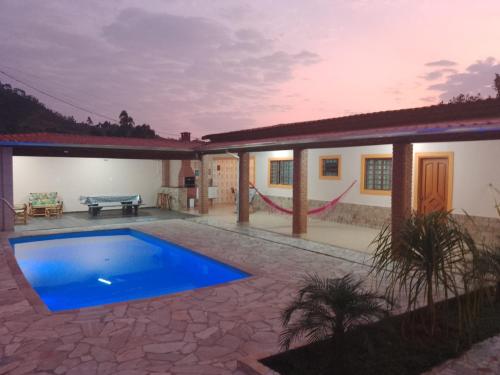 a villa with a swimming pool in front of a house at Chácara isabella in Socorro
