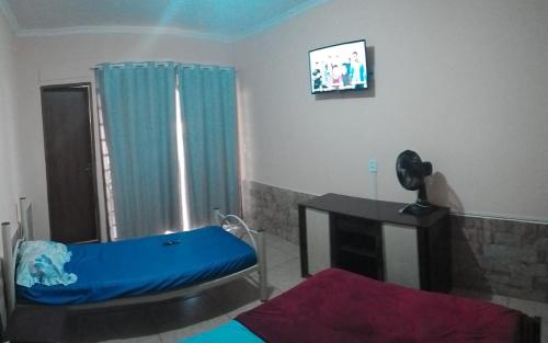 a room with a bed and a desk and a television at Chácara isabella in Socorro