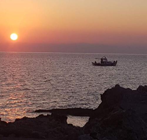 a boat in the ocean with the sunset in the background at Haris Studios in Palaiochóra