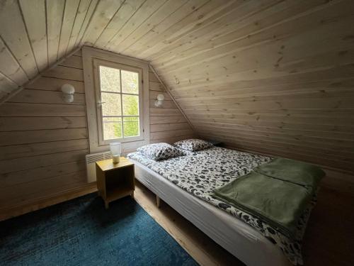 a bed in a wooden room with a window at Domki w Porcie Genaker in Giżycko