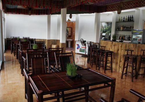 a restaurant with wooden tables and chairs and a bar at Mai Chau Sunset Boutique Hotel in Mai Chau