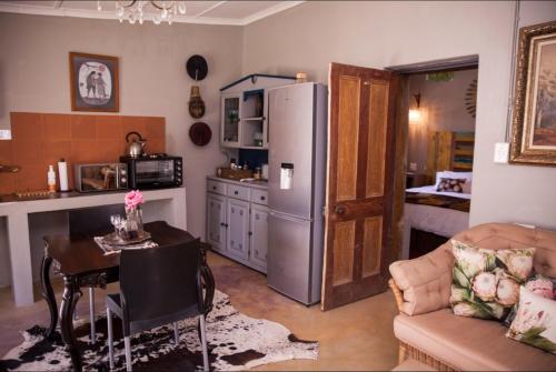 a kitchen with a refrigerator and a table in a room at Koekeloer Selfcatering Cottages in Nieu-Bethesda