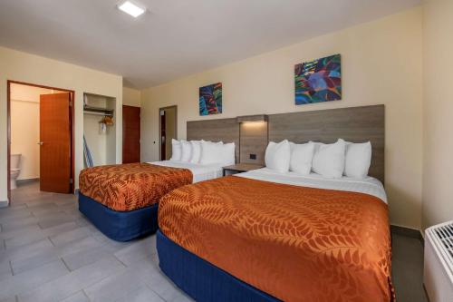a hotel room with two beds with orange sheets at Hotel Mayaguez Plaza, BW Signature Collection in Mayaguez