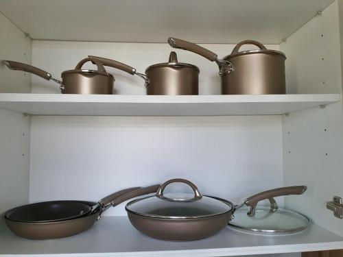 three pots and pans sitting on shelves in a kitchen at ISLA VILLA 1 amazing waterfall pool house near beach, bars & restaurants in Mactan