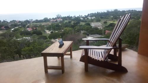 two rocking chairs and a table with a book on it at Welcoming vibes in Treasure Beach