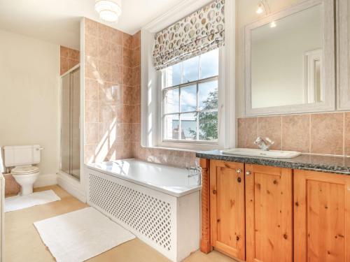baño con bañera, lavabo y ventana en Hilltop House en Tenbury