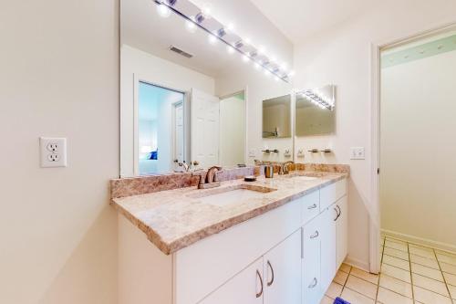 Un baño con lavabo y un espejo grande. en Sea Colony - 56053 Pinewood Dr, en Bethany Beach