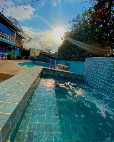a swimming pool with a blue tiled floor and the sun at Pousada Orquídeas do Guarujá in Guarujá