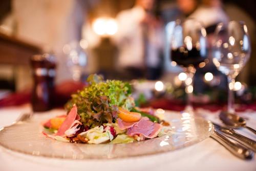 a plate with a salad on a table with a wine glass at Landhotel Altes Zollhaus in Hermsdorf