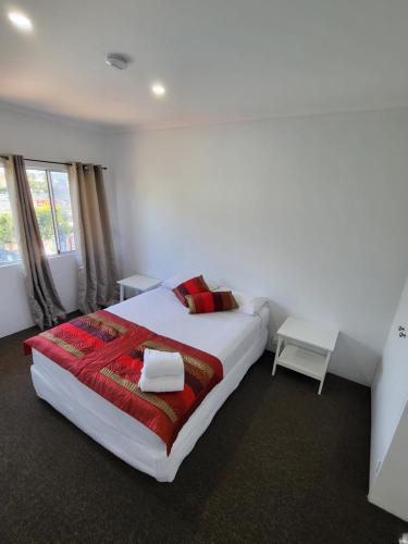 a bedroom with a large bed with a red blanket at Central Motel Mooloolaba in Mooloolaba