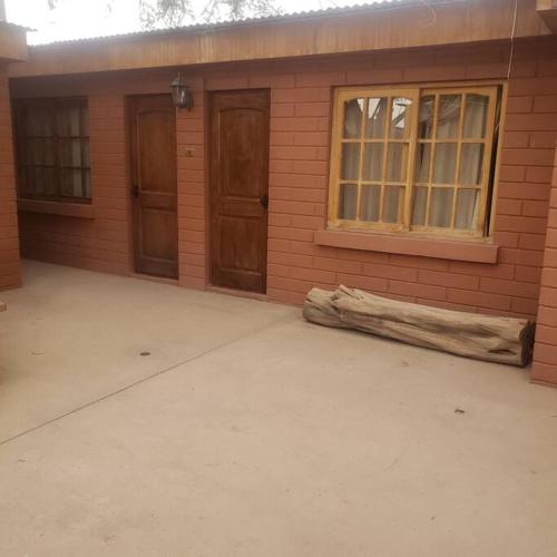 ein Gebäude mit zwei Türen und einem Baumstamm daneben. in der Unterkunft CASA VICTORIA in San Pedro de Atacama