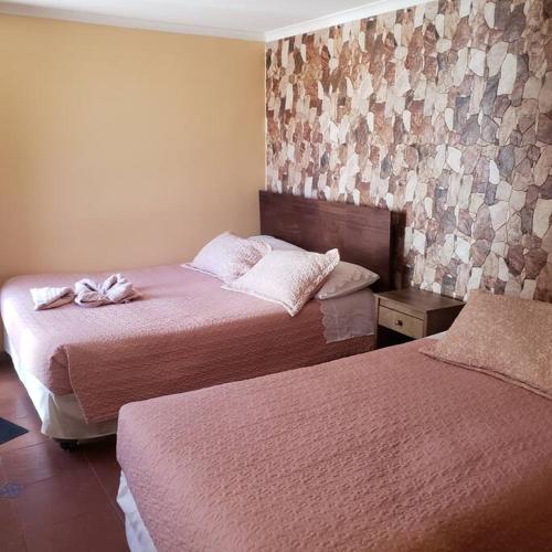 pokój hotelowy z 2 łóżkami i ścianą wyłożoną kafelkami w obiekcie CASA VICTORIA w mieście San Pedro de Atacama