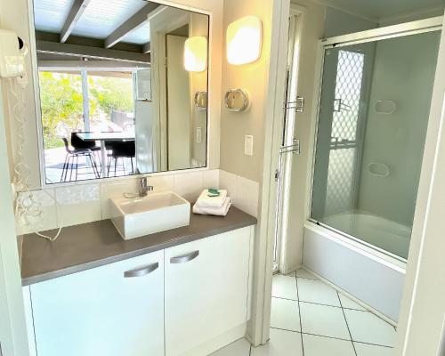 a bathroom with a sink and a mirror and a table at Kellys Beach Resort in Bargara
