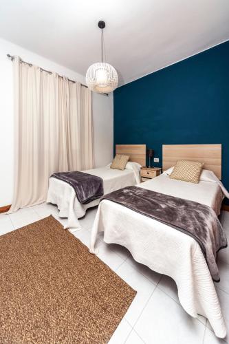 two beds in a room with a blue wall at Luxury Beach Apartment Nasa in Playa Honda