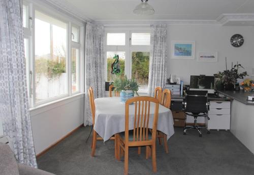 een eetkamer met een tafel en stoelen en een bureau bij Rosies Place in Oamaru