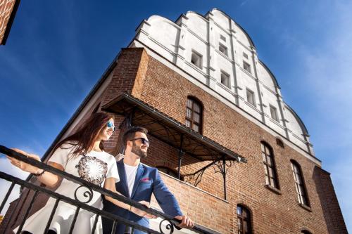 a bride and groom posing in front of a building at Hotel St. Bruno in Giżycko