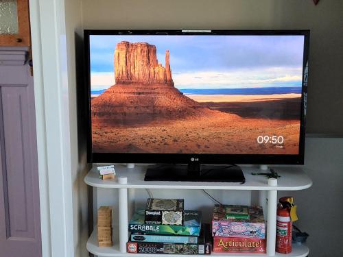 a flat screen tv sitting on a white stand with a desert at Tambo Tranquility in Mount Tamborine