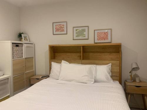 een slaapkamer met een wit bed en een houten hoofdeinde bij Rooftop infinity pool - St Kilda luxury in Melbourne