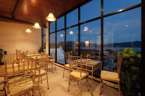 comedor con mesas y sillas y ventanas grandes en GHIELLANIQA INN, 