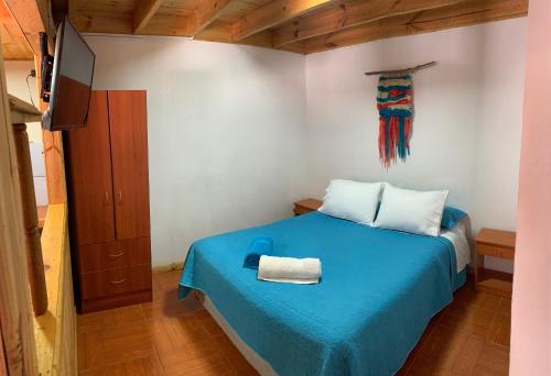 a bedroom with a blue bed and a tv at Lefun & Lafquen de Pichilemu in Pichilemu