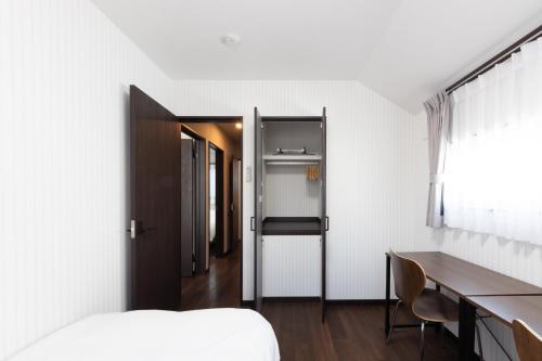 a bedroom with a bed and a desk and a window at FAMILIA糀谷 in Tokyo