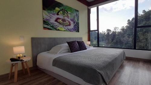 a bedroom with a large bed and a large window at Hotel Termales Tierra Viva in Manizales
