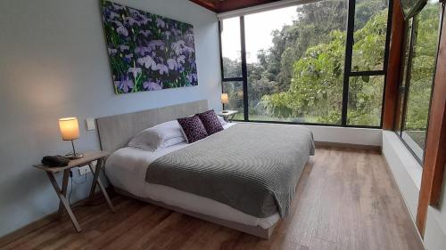 a bedroom with a bed and a large window at Hotel Termales Tierra Viva in Manizales