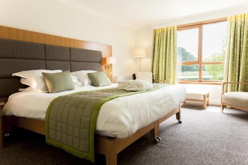 a bedroom with a large bed and a large window at Champneys Tring in Tring