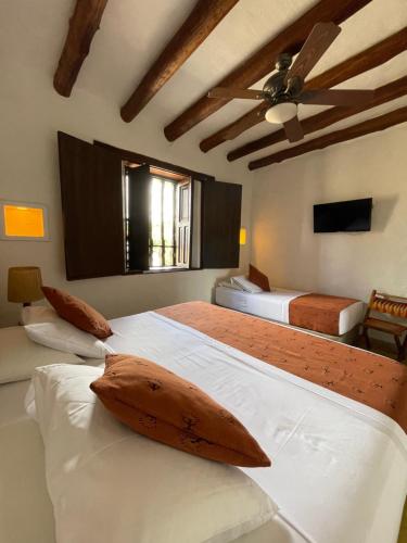 a bedroom with two beds and a ceiling fan at Hotel Hicasua y Centro de Convenciones in Barichara