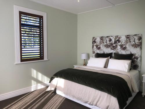 a white bedroom with a large bed and a window at River View Cottage in Kahuranaki