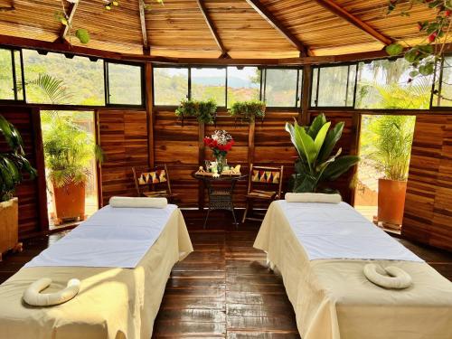 two beds in a room with wooden walls and windows at Hotel Hicasua y Centro de Convenciones in Barichara
