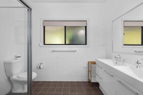 a white bathroom with a toilet and a sink at Wanda Point House - pure tranquillity and walk to beach in Salamander Bay