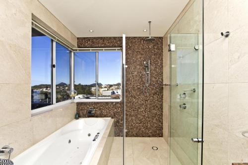 a bathroom with a tub and a glass shower at Penthouse Palace - Luxurious Harbourview Location in Nelson Bay