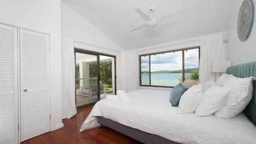 a woman laying on a bed in a bedroom with a window at Baywatch - Beachfront Bliss Executive Home in Soldiers Point