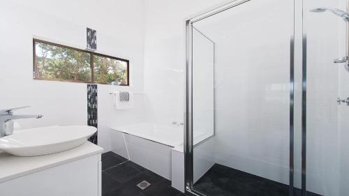 a white bathroom with a sink and a shower at Baywatch - Beachfront Bliss Executive Home in Soldiers Point