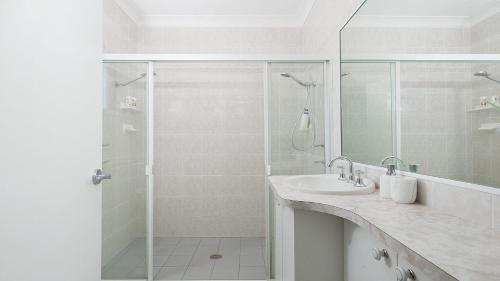 a white bathroom with a shower and a sink at The Family Entertainer - with sweeping water views in Salamander Bay