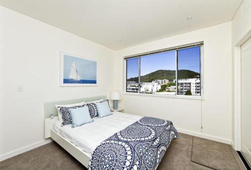 a white bedroom with a bed and a window at Harbour View Penthouse - The Perfect Location in Nelson Bay