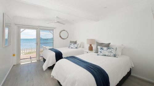 two beds in a room with a view of the ocean at The Beach Shack on Wanda - Brand New Beachfront Luxury in Salamander Bay