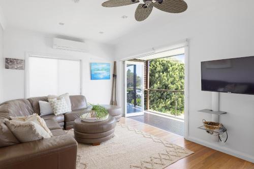 a living room with a couch and a large window at Fingal Bay Beach House - Water Views and Seconds From the Beach in Fingal Bay