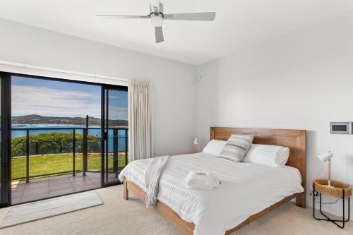 a bedroom with a bed with a view of the ocean at Above and Beyond - Beautiful Home with Heated Pool and Views in Salamander Bay