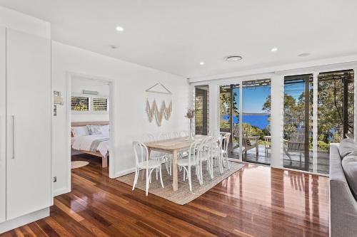 a white bedroom with a table and chairs and a bed at Driftwood in Soldiers Point