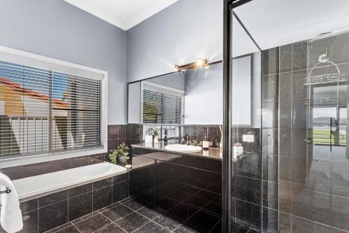 a bathroom with a shower and a tub and a sink at Above and Beyond - Beautiful Home with Heated Pool and Views in Salamander Bay