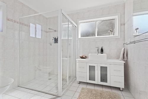a white bathroom with a shower and a sink at Driftwood in Soldiers Point