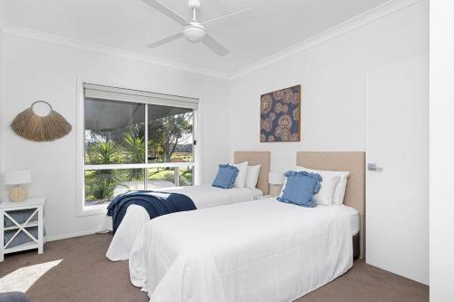 two beds in a white room with a window at The Home Resort - One Mile Beach in One Mile