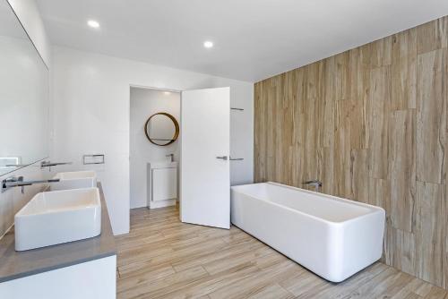 baño con bañera blanca grande y pared de madera en The Zenith, en Shoal Bay