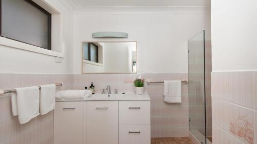 a white bathroom with a sink and a mirror at Dutchie's Dream - Glorious Views And Opposite Dutchies Beach in Nelson Bay